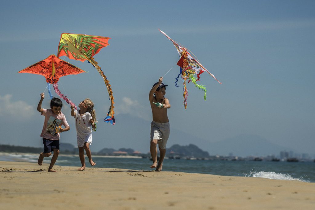Children playing with kites on the beach: Four Seasons Resort The Nam Hai